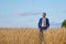 Young farmer businessman in shirt and tie inspects his fields with crops