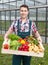 Young farmer in front of a greenhouse with vegetables