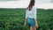 Young farmer Girl in a shorts walks across the field in suset light. Modern farming, happy youth and profession concept. Organic P