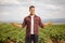 Young farmer with gloves posing on a grape vine field