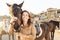 Young farmer having fun with horses inside stable - Happy girl playing with animals in corral ranch