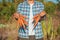 Young Farmer Man staying and Holding bunch harvested Fresh Carrot in Garden. Natural Organic Bio Vegetables. Country Village