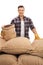 Young farmer posing with burlap sacks with coffee