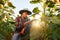 A young farmer sits on his shorts and checks the quality of the crop of sunflower.