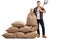 Young farmer standing next to pile of burlap sacks and holding s