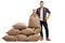 Young farmer standing next to pile of sacks and holding burlap s