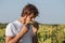 Young farmer tasting ripe corn cob at corn field