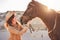 Young farmer woman playing with her bitless horse in a sunny day inside corral ranch - Concept about love between people and