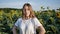 Young farmer woman poses against background of grown sunflower crop. young girl stands on background of field of sunflowers