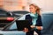 Young fashion business woman with laptop leaning on her car