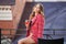 Young fashion woman in red tweed jacket and skirt suit at sidewalk cafe