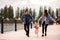 A young, fashionable family walks along the embankment of the river, mom and dad hold daughter`s hands