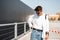 Young fashionable man model in a T-shirt in a white shirt in vintage blue jeans in sunglasses walks around the city