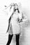 Young fashionable pretty woman or girl with beautiful long blonde hair in waist coat of white fur with hood pink