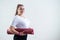 Young fat caucasian woman holding a sport mat. Charming plus size model in sportswear stands on a white background