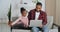 Young father afro american guy sits on couch with little cute girl his daughter teaches child how to use laptop play