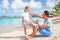 Young father applying sun cream to daughter nose on the beach. Sun protection