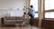 Young father dancing on heated wooden floor with small son.