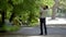 A young father with his son in his arms touches a branch on a tree in the park.