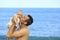 Young father holding baby on the beach near ocean with lighthouse.