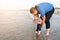 Young father holding his child over sea water