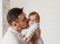 Young father kisses baby daughter in a light room close-up