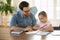 Young father and little daughter studying at home