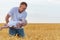 Young father playing with baby. Child flies over field in dads hands. Ripe wheat field