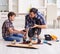 Young father repairing skateboard with his son at home