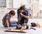 Young father repairing skateboard with his son at home