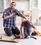 Young father repairing skateboard with his son at home