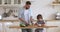 Young father teaching kid son cutting vegetable salad in kitchen