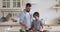 Young father teaching little school boy son chopping fresh vegetables.