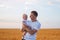 Young father tenderly holding baby on wheat field background. Portrait of happy father and child