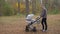 A young father walks with a stroller in the park. A man with a newborn baby.