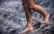 Young feet in the streams of water on the steps of the fountain.