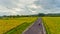 A young fellow of Caucasian appearance rides a sports motorcycle on the road between rice fields at sunset.