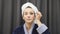 Young female applying mascara on eyelashes. Woman in blue bathrobe and towel on head holding mascara and doing makeup at home. Wom