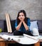 The young female architect is sitting on sofa beside white safety helmet ,working on project,with serious emotion