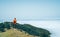 Young female backpacker dressed orange waterproof jacket hiking by the mountain above the cloud route at the end of February on