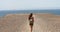 Young female backpacker enjoying ocean breeze and looking Fuerteventura Island in front of her. Hiker traveler girl walking.