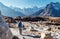 Young female backpacker following Everest Base Camp trekking route using trekking poles and enjoying valley view with Ama Dablam