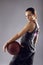 Young female basketball player posing on grey background