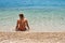 Young female in bikini sitting in shallow sea, left side