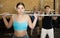 Young female bodybuilder performing strength and endurance exercises during group barbell lifting in CrossFit class