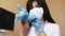 Young female brunette doctor with long hair in surgical mask dressing medical gloves while sitting at the table in her