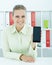 Young female businesswoman showing smartphone in hand sitting at office.