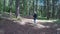 Young female camper with backpack slowly walking and admiring the mountain forest -