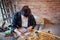 Young Female Carpenter Drawing And Measuring Woodwork Design In Garage Workshop