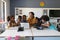 Young female caucasian teacher teaching laptop to african american elementary students in class